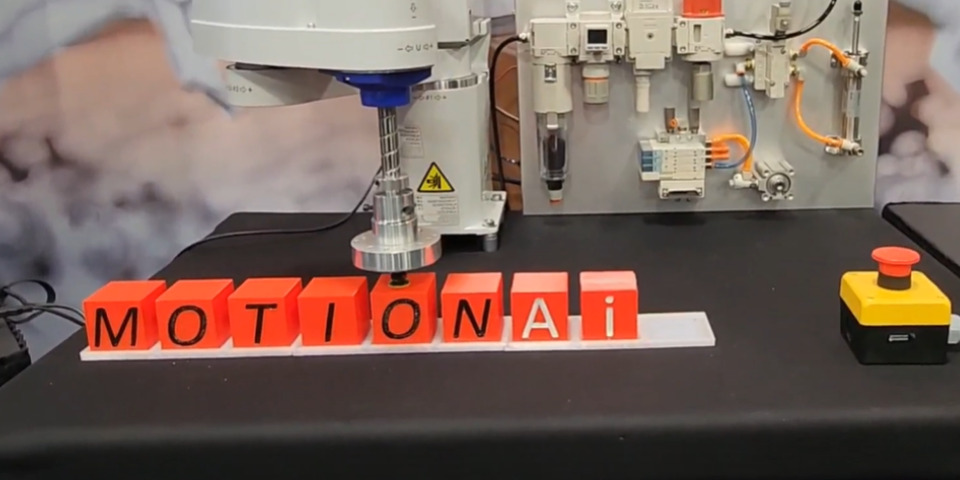 A robot spelling out "Motion Ai" with small blocks