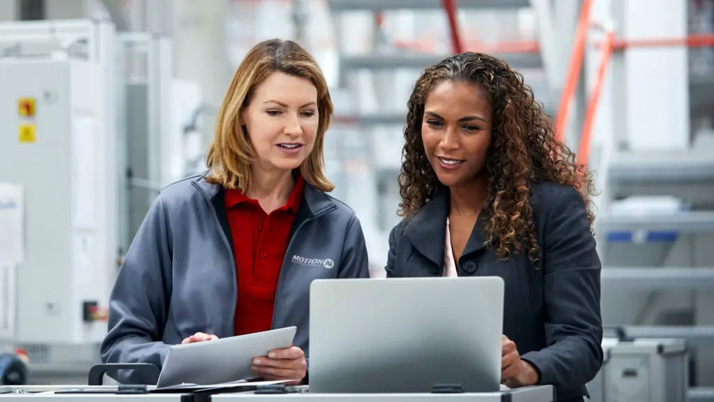 Two female Motion Automation Intelligence co-workers reviewing reports in plant