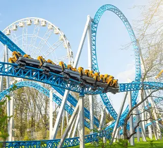 People riding on fast moving rollercoaster in clear blue skies