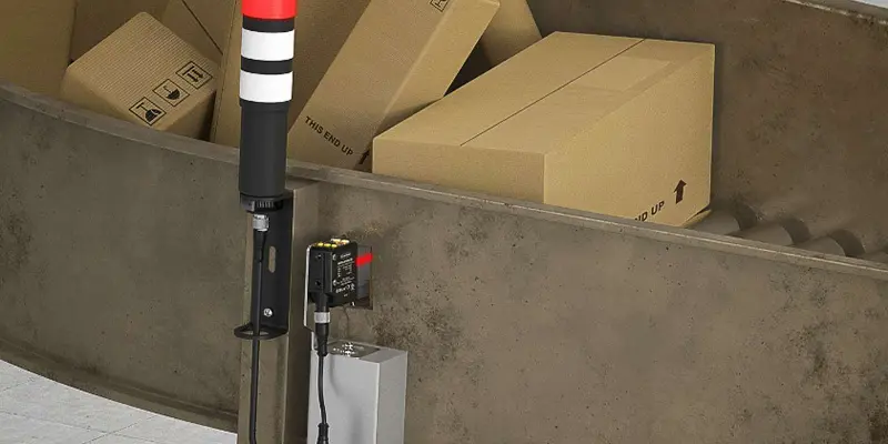Close-up of Banner Engineering TL30 Basic Series tower light monitoring packages rolling on a conveyor in a distribution facility