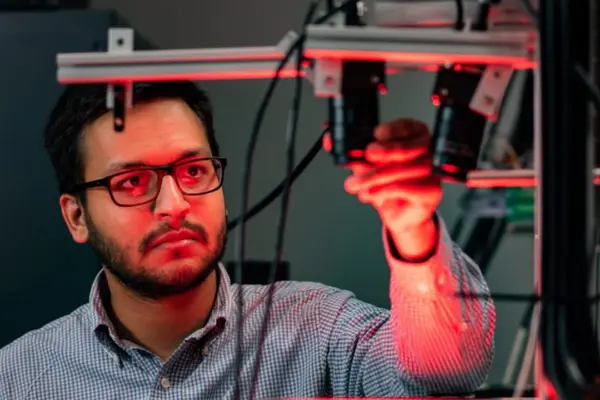Close-up of a man working a robot machine with red light on his face