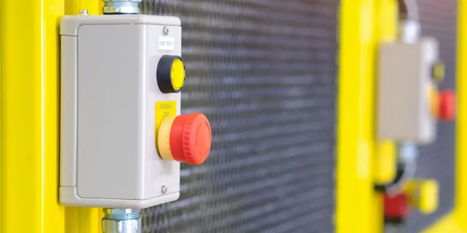 Emergency stop button with blurred industrial facility background