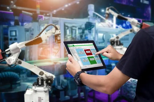Smart industry control, hands holding a tablet on blurred automation machine as background